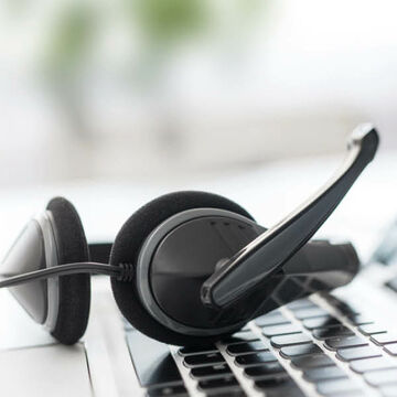 Ein Headset liegt auf der Tastatur eines Laptops